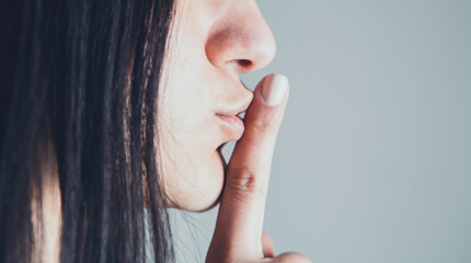closeup girl showing silence gesture with finger on lips