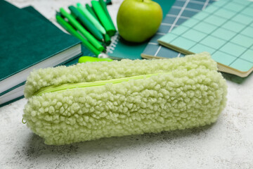 Pencil case and stationery on light background