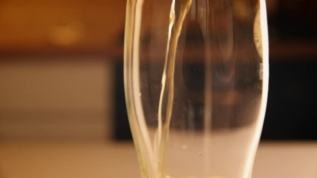 Beer pouring in a glass from bottle with bubbles, close up