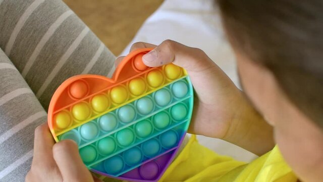 Colorful antistress sensory toy fidget push pop it in kid's hands.
