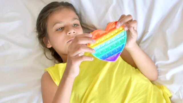 Colorful antistress sensory toy fidget push pop it in kid's hands.