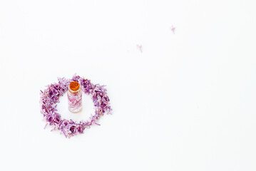 Cosmetic bottle close up with lilac flowers on the white background