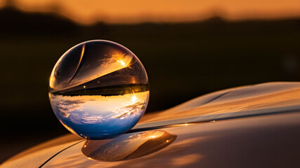 Crystal ball sunset shot with reflections on a car roof at Buchhofen, Bavaria, Germany