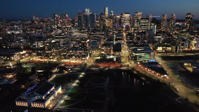 Cinematic 4K drone, after sunset, night clip of MOHAI downtown Seattle with illuminated streets and offices looking from South Lake Union in Seattle, Washington during blue hour