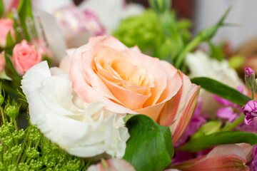 A closeup view of a floral bouquet, featuring a peach colored rose.