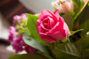 A closeup view of a floral bouquet, featuring a petite magenta rose.