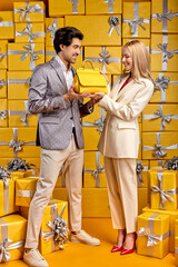 Pleasant Guy Give New Yellow Hand Bag To Girlfriend, Congratulating, Please Woman, Celebrating Birthday Or Anniversary, Standing Surrounded By Many Gifts Boxes, Posing