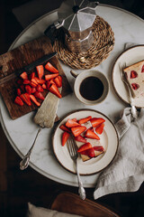 curd dessert with fresh strawberries and a cup of black coffee. fresh dessert with sliced raw strawberries on a marble table top view. moka coffee pot and a cup with black coffee. vintage cutlery