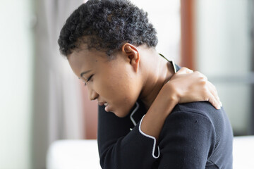 Fototapeta na wymiar Black African woman suffers from shoulder joint pain, shoulder stiffness or osteoporosis or having pain at injection site as a side adverse effect after vaccination at upper arm muscle