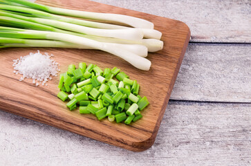 Green onion or scallion on wooden board, fresh spring chives