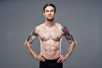 Fototapeta na wymiar sporty man pumped up press acting out on his arms cropped view gray background