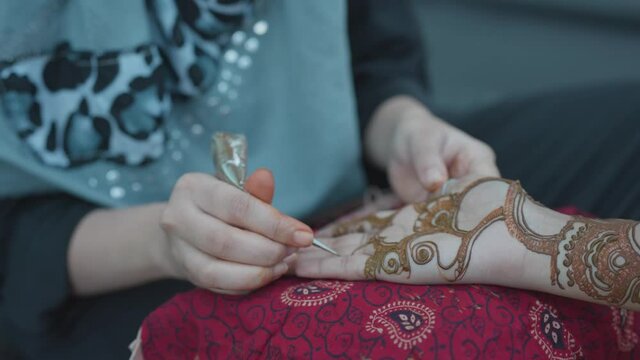 Woman applying Traditional Indian mehndi with henna paste with on Bride&rsquo;s hand in Indian wedding.