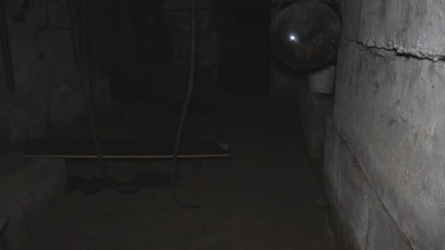 A man walks through a dark old abandoned basement. Point of view. Lower key