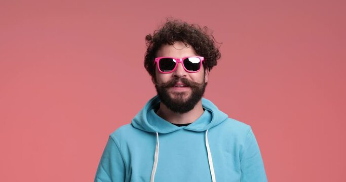 young casual man putting his sunglasses on, laughing and showing off with his cool style