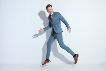 elegant young businessman in blue suit leaping up in the air
