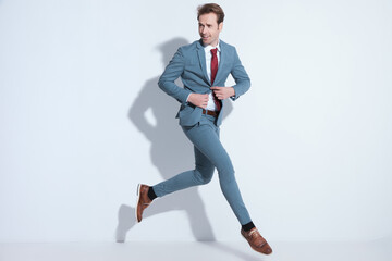 dynamic businessman jumping and unbuttoning blue suit