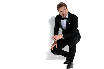 sexy businessman squatting, resting his arms on his lap
