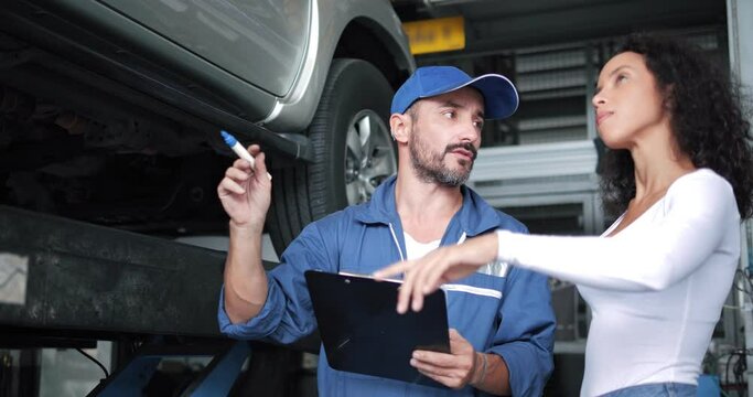 Vehicle technician mechanic having conversation with customer about car repairing budget cost and insurance. Woman listening to mechanic at maintenance garage service center workshop. Automotive