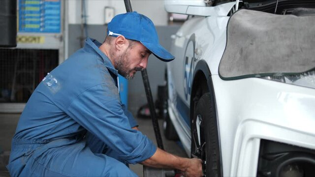 Professional car mechanic changing car wheel in auto repair service.