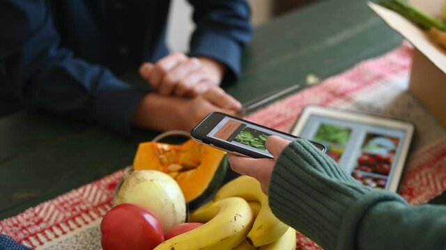 オンラインスーパーマーケットで野菜の配達を注文する男女