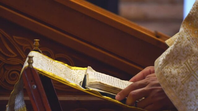 The book is in the hands of a priest or clergyman