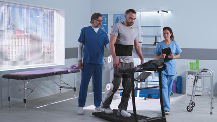 Doctors discussing rehabilitation results near patient in exoskeleton