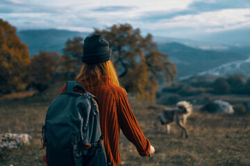 woman hiker with backpack on nature landscape dog