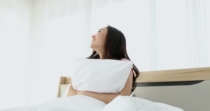 Young shy introvert asian woman waking up and hugging pillow feling hopeful in love