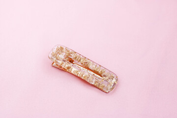Gold color hair clip on pink background.