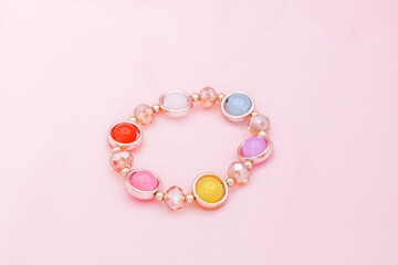 Colorful beads bracelet on pink background.
