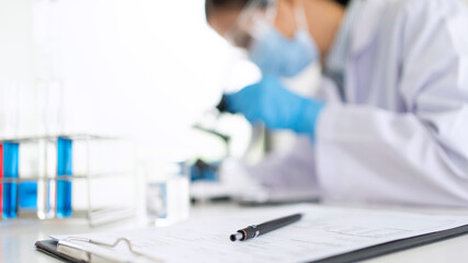 scientists researching in laboratory in white lab coat, gloves analysing, looking at test tubes...