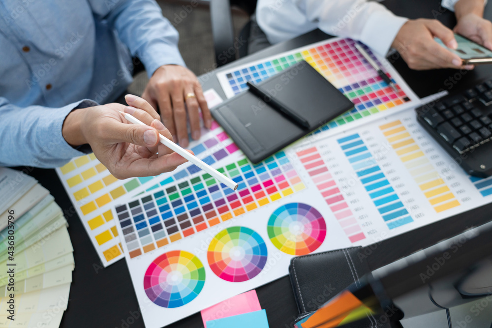 Poster graphic designer team working on web design using color swatches editing artwork using tablet and a 