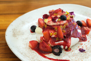Gourmet strawberry Pavlova cake with fresh berries topping and layers of whipped cream and meringue served on a plate,