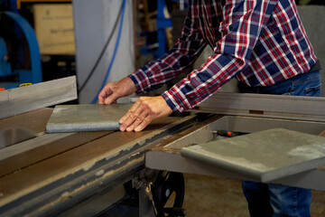 construction worker in a factory saws planks made from recycled plastic waste