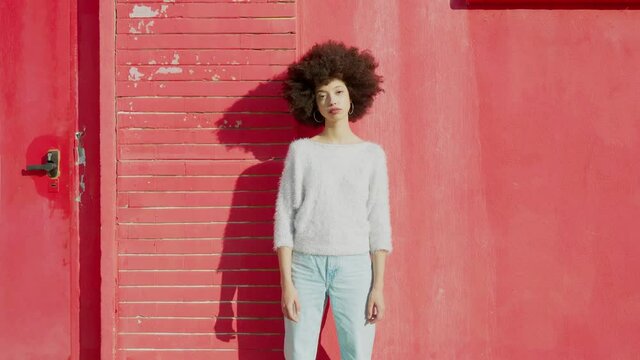 Young sad woman standing in front of red wall