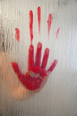 bloody hand behind frosted glass window or shower screen