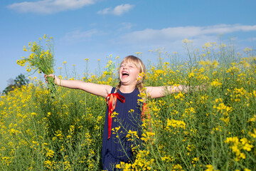 Little blonde girl is playing in a meadow flower