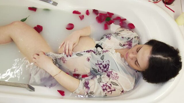 Pregnant girl in underwear takes a bath with milk and rose petals
