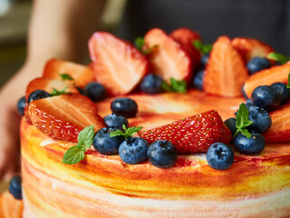 Homemade baking. Close-up of a cake decorated with strawberries, blueberries, mint leaves.