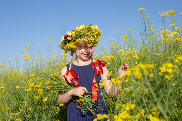 Little blonde girl is playing in a meadow flower