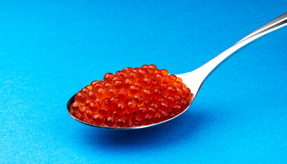 Red caviar in spoon isolated on blue background