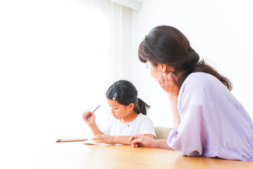 お家でお母さんとお勉強する女の子