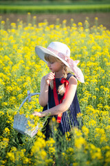 Little blonde girl is playing in a meadow flower