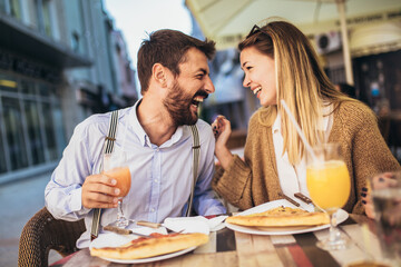 Attractive and happy young couple having good time in cafe restaurant. They are smiling and eating a pizza.