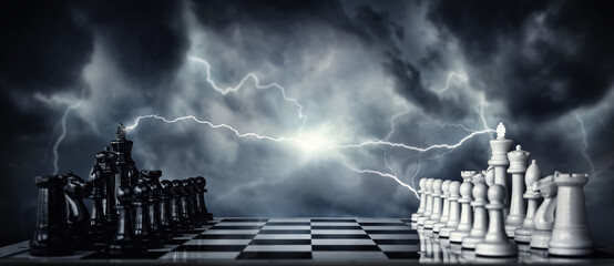 Chess pieces on a chessboard against the backdrop of a stormy sky and flashing lightning. The game of chess as a symbol of strategy, leadership, tactics and business victories.  - obrazy, fototapety, plakaty