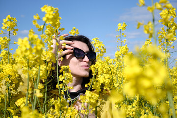 Girl and yellow flowers of rapeseed. Oilseed plant. Travel outside the city. Summer sunny weather.