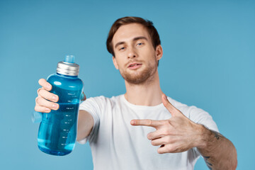 man in white t-shirt water bottle quenching thirst cropped view blue background