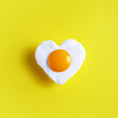 Heart shaped egg on yellow background, for the world egg day.