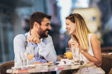 Attractive and happy young couple having good time in cafe restaurant. They are smiling and eating a pizza.