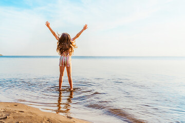 Little girl jumping on the beach in the water, the concept of a fun summer vacation